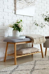 Vase with lilac flowers on soft bench in room