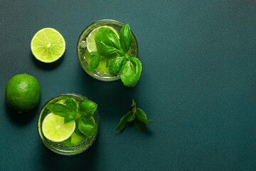 Fresh iced lemonade with basil and lime on dark green background top view, copy space for your...