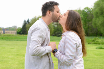 Beautiful loving happy couple kissing in park on spring day