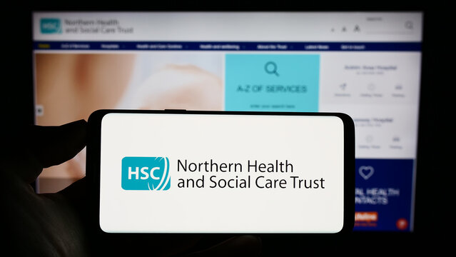 Stuttgart, Germany - 07-12-2023: Person Holding Cellphone With Logo Of Health And Social Care (HSC) In Northern Ireland On Screen In Front Of Webpage. Focus On Phone Display.