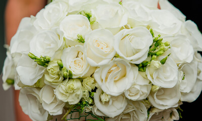 dding bouquet of white roses in the hands of a woman