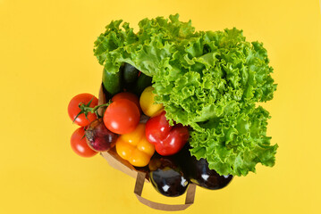 Paper bag with fresh vegetables on yellow background. Healthy food concept