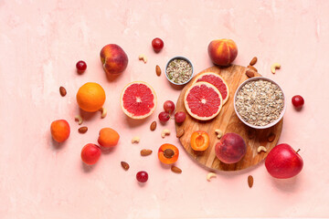 Wooden board with different healthy products on pink background