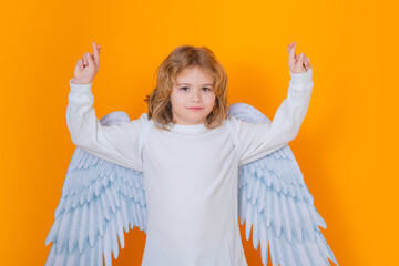 Child angel crossed fingers with lucky and hope, good luck. Cute angel kid, studio portrait. Blonde...