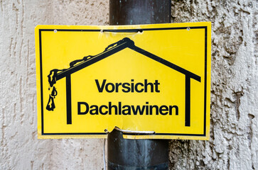A sign on the wall warning in German about snow falling from the roof. English translation: Caution, roof avalanches