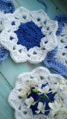 Fototapeta na wymiar Blue, white crochet elements and orchid. Crochet texture, place for an inscription, adapted for mobile phone