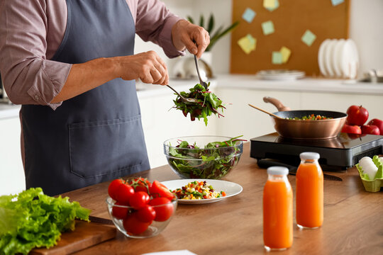 Mature man making vegetable salad in kitchen, closeup