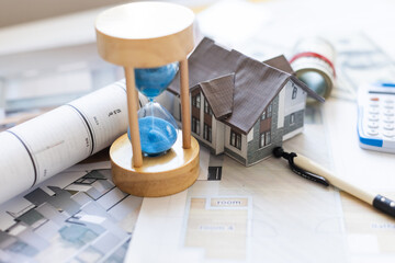 Wooden house and clock. Businessman counting money. Payment of deposit or advance payment for...