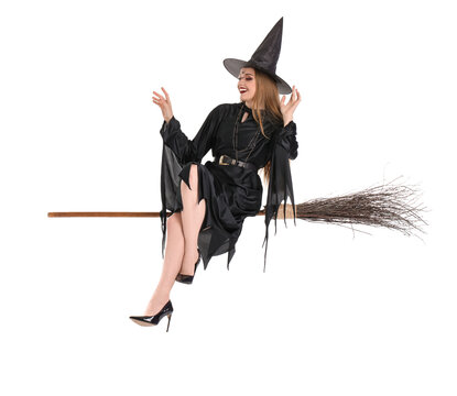 Beautiful young witch sitting on broom against white background