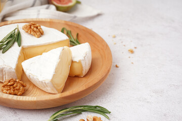 Plate with pieces of tasty Camembert cheese on light background