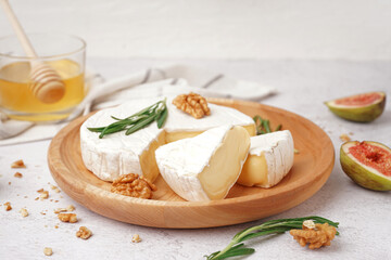 Plate with pieces of tasty Camembert cheese on light background