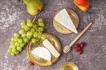 Plates with pieces of tasty Camembert cheese on grey background