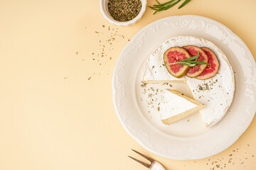 Plate with pieces of tasty Camembert cheese on yellow background