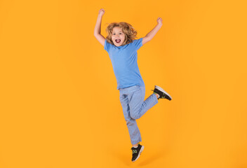 Funny boy jumping in air. Boy jumping. Full size of kid boy have fun jump up isolated over yellow background.
