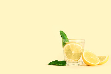 Glass of tasty mojito and lemon on color background