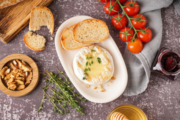 Plate of tasty baked Camembert cheese on grey background