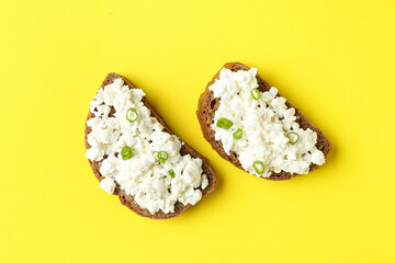 Tasty sandwiches with cottage cheese on yellow background