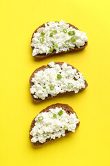 Tasty sandwiches with cottage cheese on yellow background