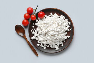 Plate of tasty cottage cheese and fresh tomatoes on grey background