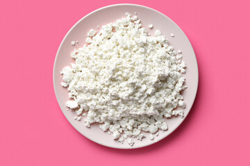 Plate of tasty cottage cheese on pink background