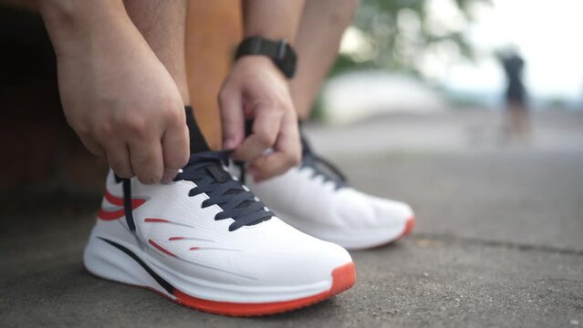 Male athlete tying shoelaces at the park.
