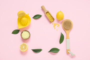 Frame made of lemon body scrub with juicer, sea salt and massage brush on pink background