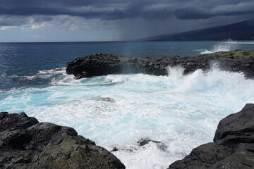 waves crashing on lava rocks on the tropical island of La Réunion, France on a stormy day