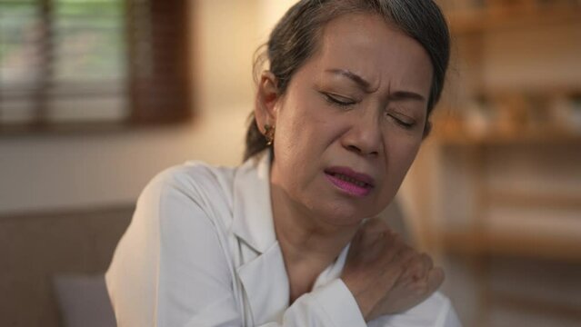 Asian senior lady is demonstrating suffering from shoulder pain.