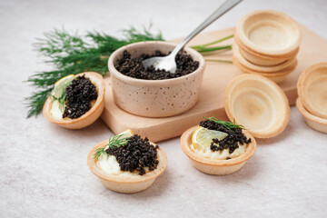 Fototapeta premium Tasty tartlets with black caviar on light background