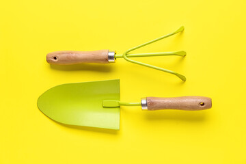 Gardening rake and shovel on yellow background