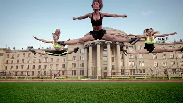 Group of cheerleaders in action. Concept of unity and team sport. Training at college high school with young female teenagers. Cheerleading person dance with team support, motivation and hands for