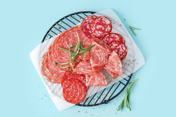 Grid with slices of tasty salami on blue background