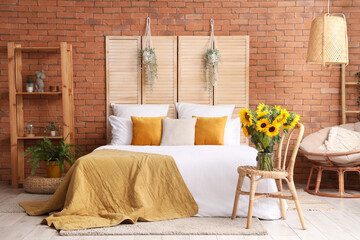 Vase with beautiful sunflowers on wicker chair in interior of stylish bedroom