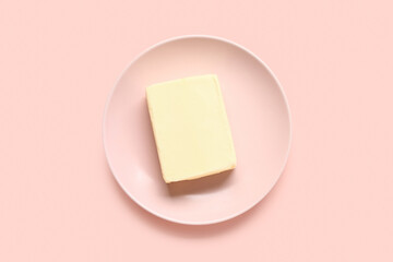 Plate with fresh butter on pink background