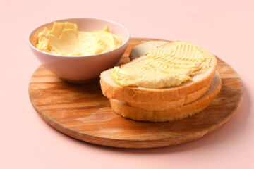 Bowl with fresh butter and tasty toast on pink background