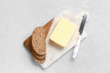 Board with fresh butter and bread on white background