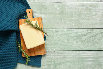 Board with fresh butter and rosemary on green wooden background