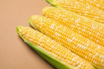 Fresh corn cobs on brown background