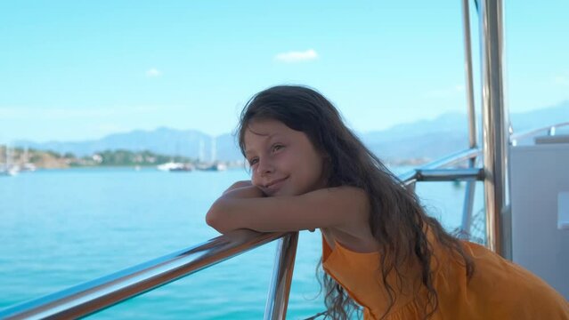 Child on deck against blue waves. A dreamy young girl relax on boat deck during slowly sailing in the open sea during sunny day.