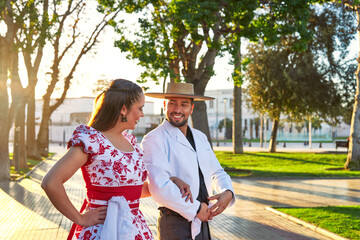 portrait young latina american man dressed as a huaso leads a woman by the arm to dance cueca...