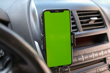 Mobile phone on the car air vent.Blank with green screen.Mock up smart phone in car.