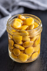 Lupini beans in brine. Pickled lupin in jar on black table.