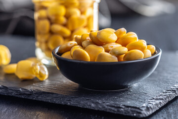 Lupini beans in brine. Pickled lupin in bowl on black table.