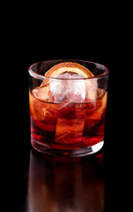red negroni drink with campari and vermouth on wooden table with orange close-up on black background