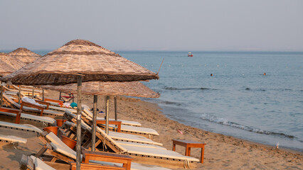 Empty sun loungers and umbrellas at sunset in Gökçeada Aydincik (Kefalos) beach. Çanakkale Turkey