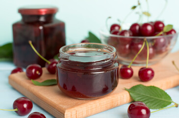Jar with tasty homemade cherry jam on wooden table