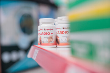 Drugstore shelves fiiled with cardiology bottle pills ready for clients to come and buy during medical visit. Pharmacy also carried a variety of other products, such as bandages and cold medicine.