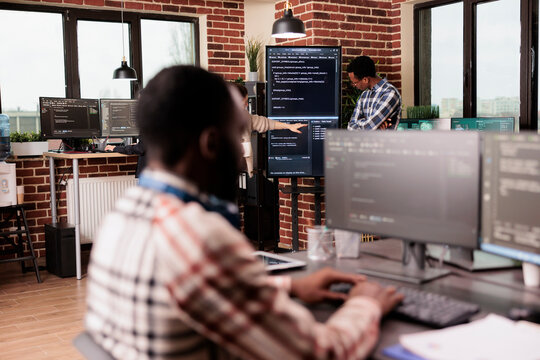 Diverse system engineers working on it project for the company network technology, utilizing their expertise in coding systems. Software developer programming big data in agency office.