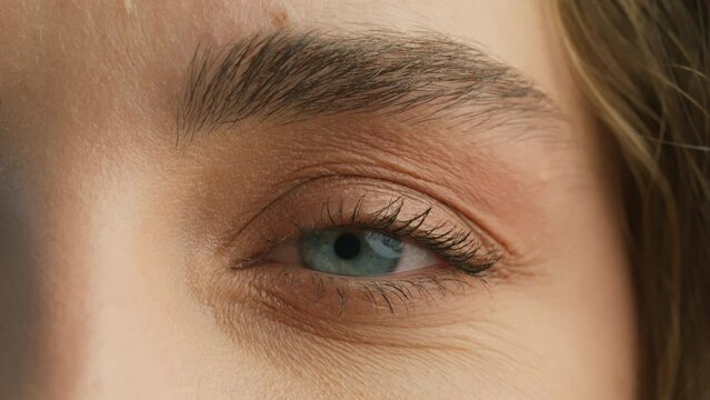Natural Beauty with thick eyebrows and mimic wrinkles. Smiling woman with long eyelashes and attractive face. Slow motion beauty. Close up young attractive girl opening her Beautiful blue azzure eyes