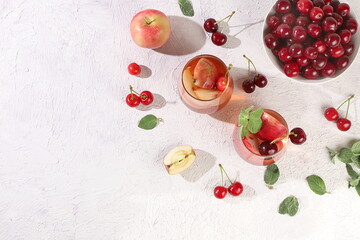 Iced cherry tea or cocktail with mint and lbd,recipe for refreshing summer drink.Glass with apple fruit lemonade on light concrete table,detox diet and weight loss concept,menu for restaurant,